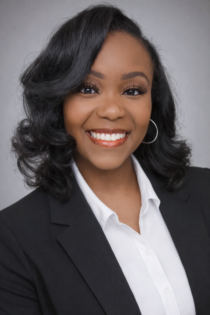 Professional headshot of a smiling woman with curly black hair, wearing a black blazer over a white shirt, reflecting Early Start's commitment to diverse leadership in pediatric therapy.